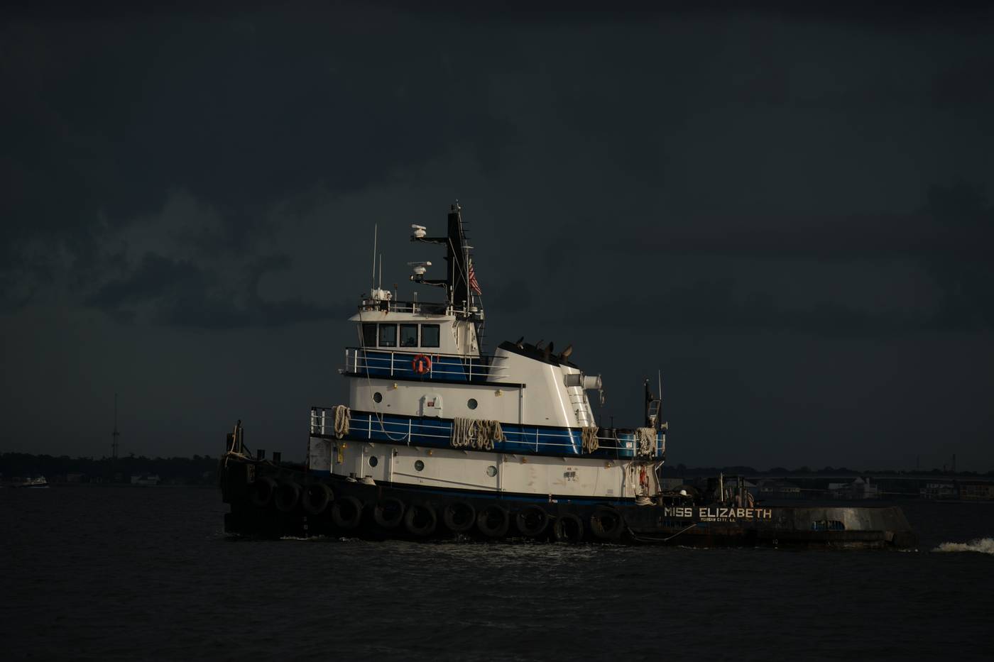Tugboat Miss Elizabeth navigates dark waters under a stormy sky
