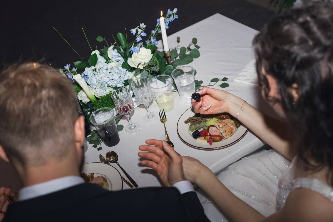 A couple enjoys a romantic wedding reception dinner with floral centerpieces and candlelight