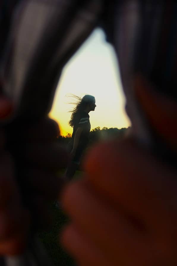Silhouette of a person with windblown hair against a golden sunset sky