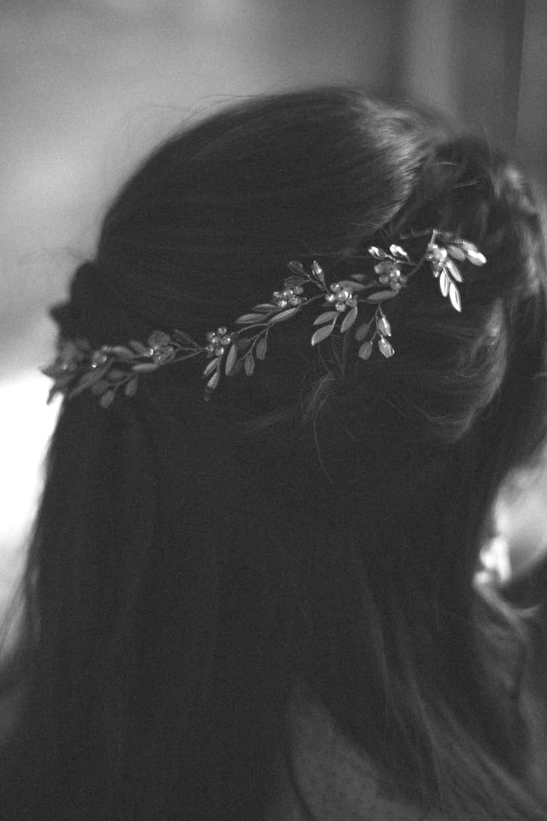 Bride's braided hair adorned with a delicate floral and crystal hairpiece during a wedding