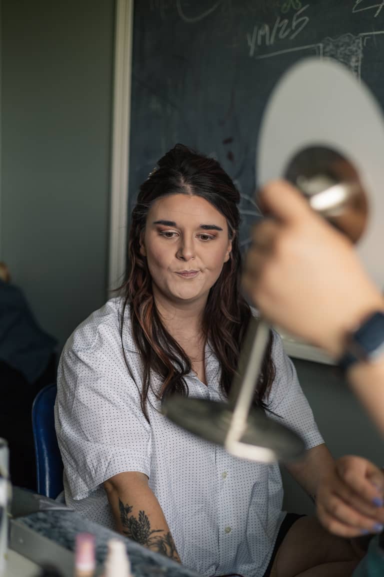 Bride getting makeup done in a casual setting before wedding ceremony