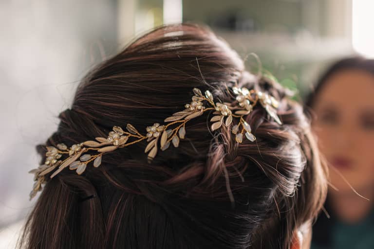 Close up of a bride's braided hair adorned with a delicate gold and crystal hairpiece