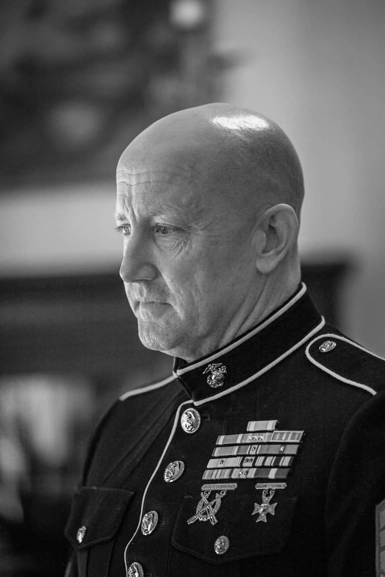 Groom in military uniform with medals looks thoughtfully into the distance during wedding ceremony