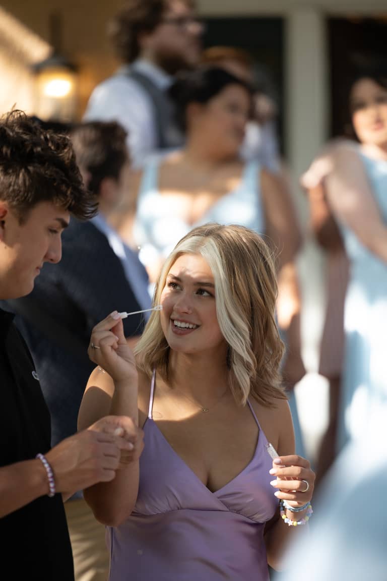 Wedding guests laugh and blow bubbles outdoors in bright sunlight