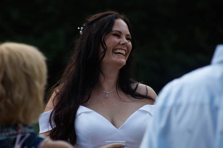 Joyful bride laughs outdoors in a white dress at her wedding celebration