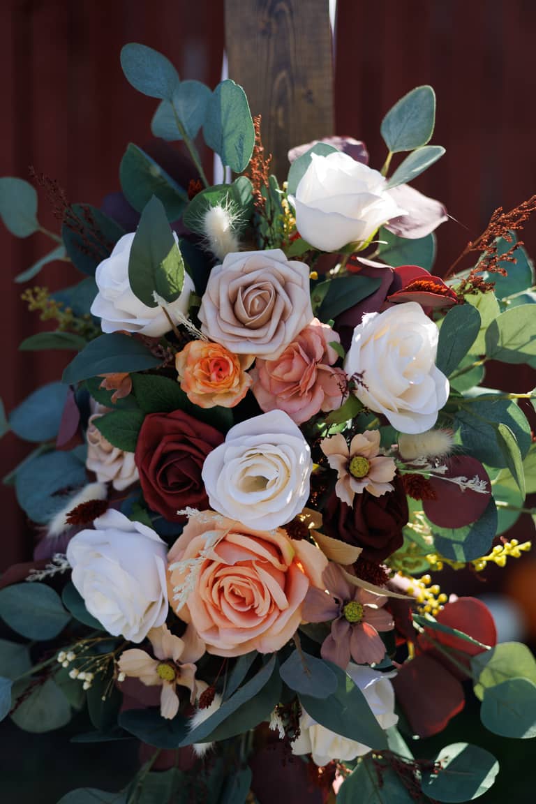 A rustic wedding bouquet with roses, eucalyptus, and dried flowers against a dark background