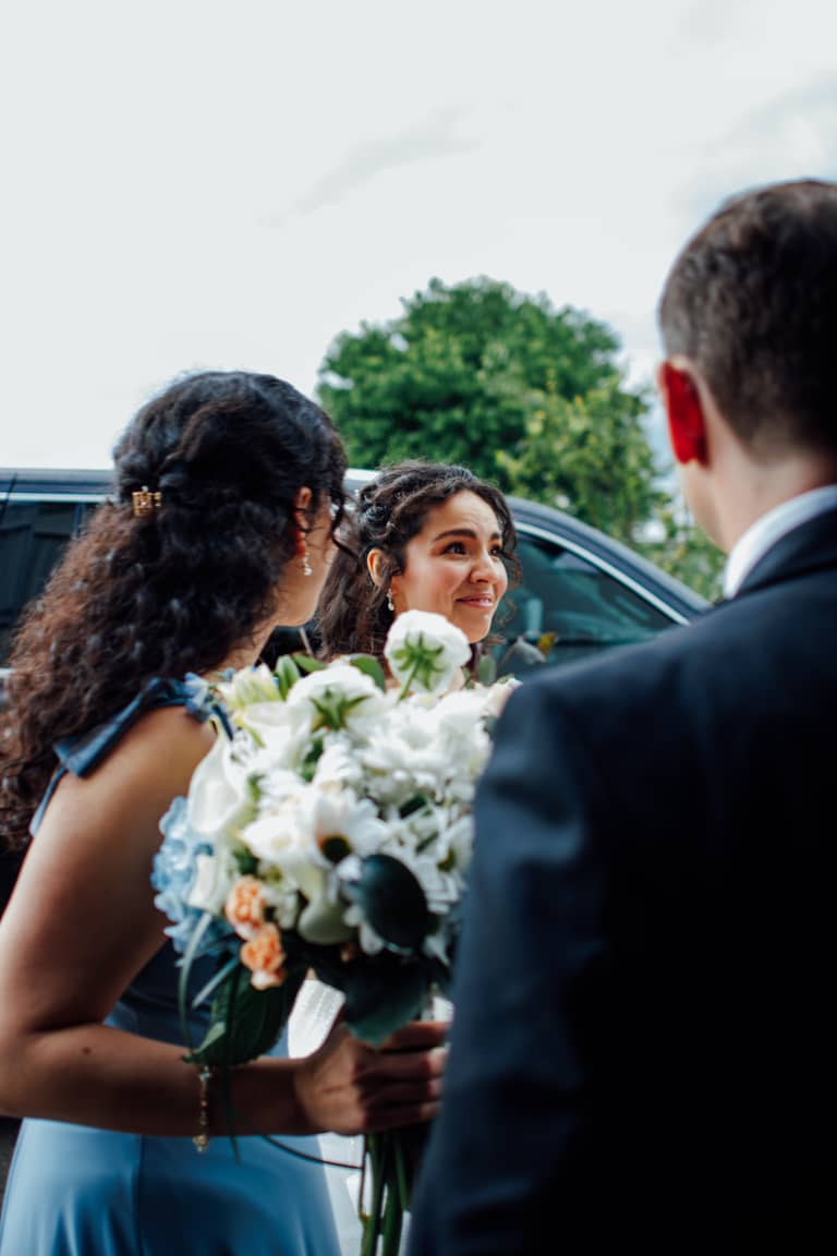 Bride smiles warmly at groom while holding a bouquet, wedding day