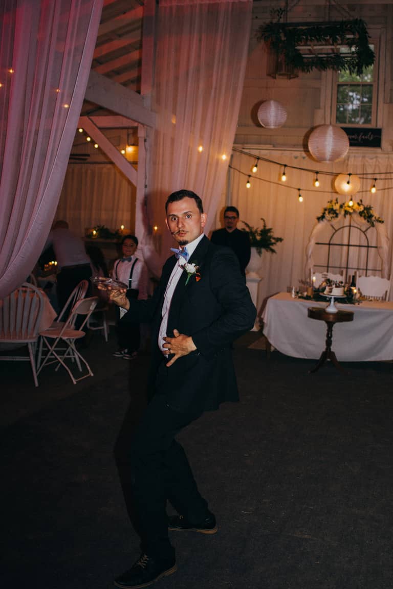 Groom dances joyfully at wedding reception in rustic barn venue