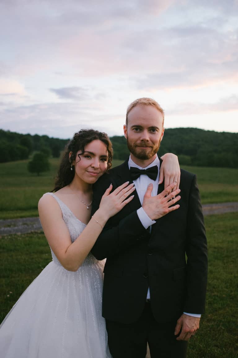 Newlyweds embrace outdoors at dusk with a gentle, loving mood