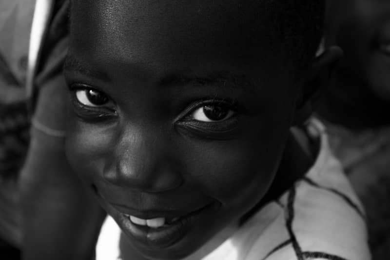 Close-up black and white portrait of a smiling child with bright eyes
