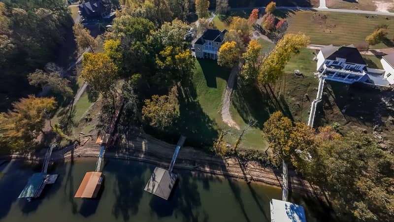 Aerial view of lakefront homes with docks surrounded by colorful autumn trees