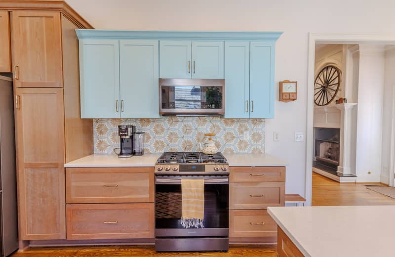 Modern kitchen with light blue cabinets, stainless steel appliances, and wood accents