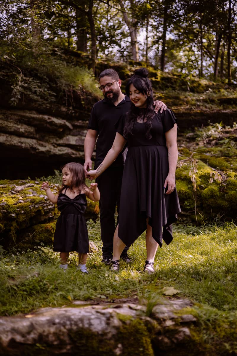 Family portrait in a mossy forest with a young girl reaching out